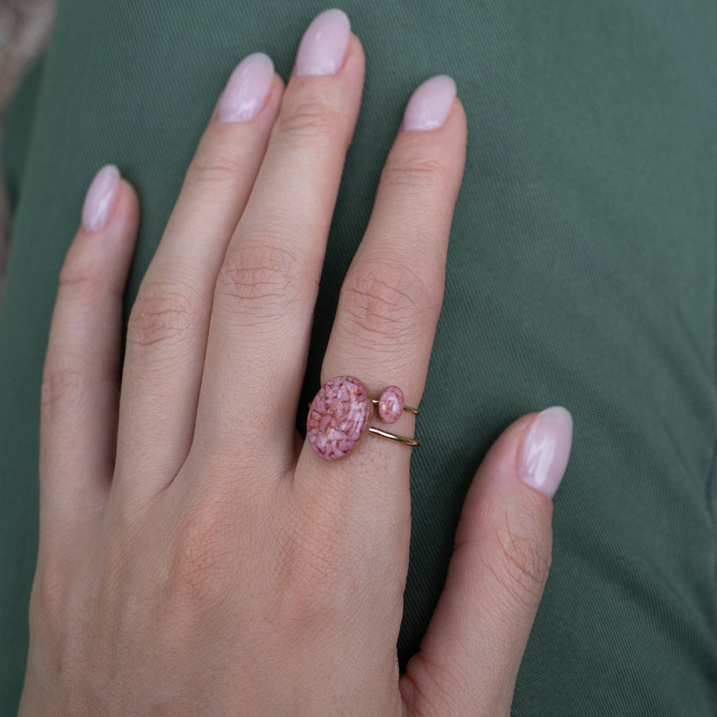 
                  
                    Delicate oval Rhodonite ring with tiny Rhodonite stone pieces captured in glass like resin in three crystal sizes.
                  
                