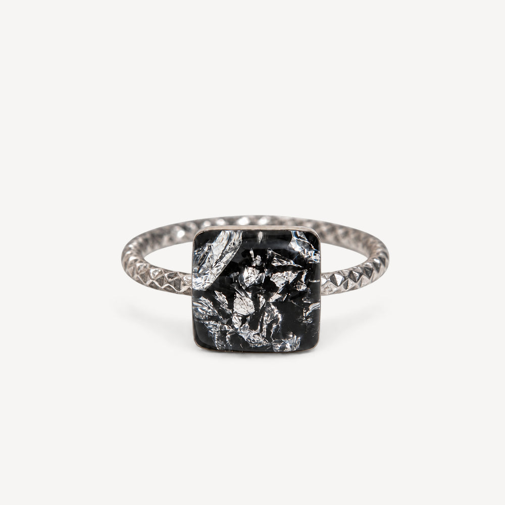 Teal gemstone in a black setting on a white background