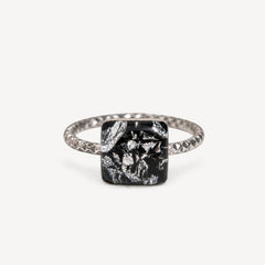 Teal gemstone in a black setting on a white background