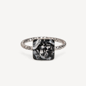 Teal gemstone in a black setting on a white background