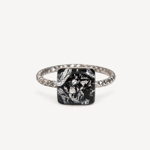 Teal gemstone in a black setting on a white background
