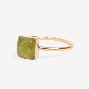 White delicate ring with green gemstone peridot square stone on a white background