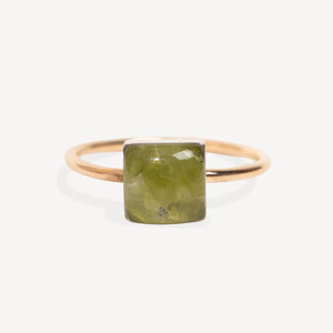 A minimalist ring featuring a square-cut olive green gemstone in a polished rose gold setting, presented on a clean, light off-white background.