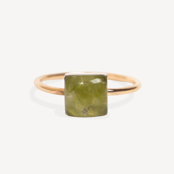 A minimalist ring featuring a square-cut olive green gemstone in a polished rose gold setting, presented on a clean, light off-white background.