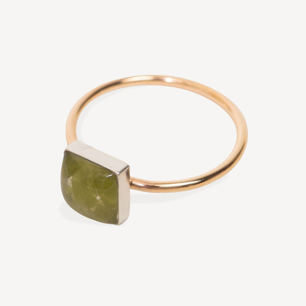 White delicate ring with green gemstone peridot square stone on a white background