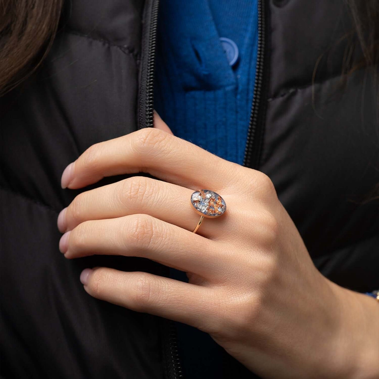 Hand wearing a ring with a blue background
