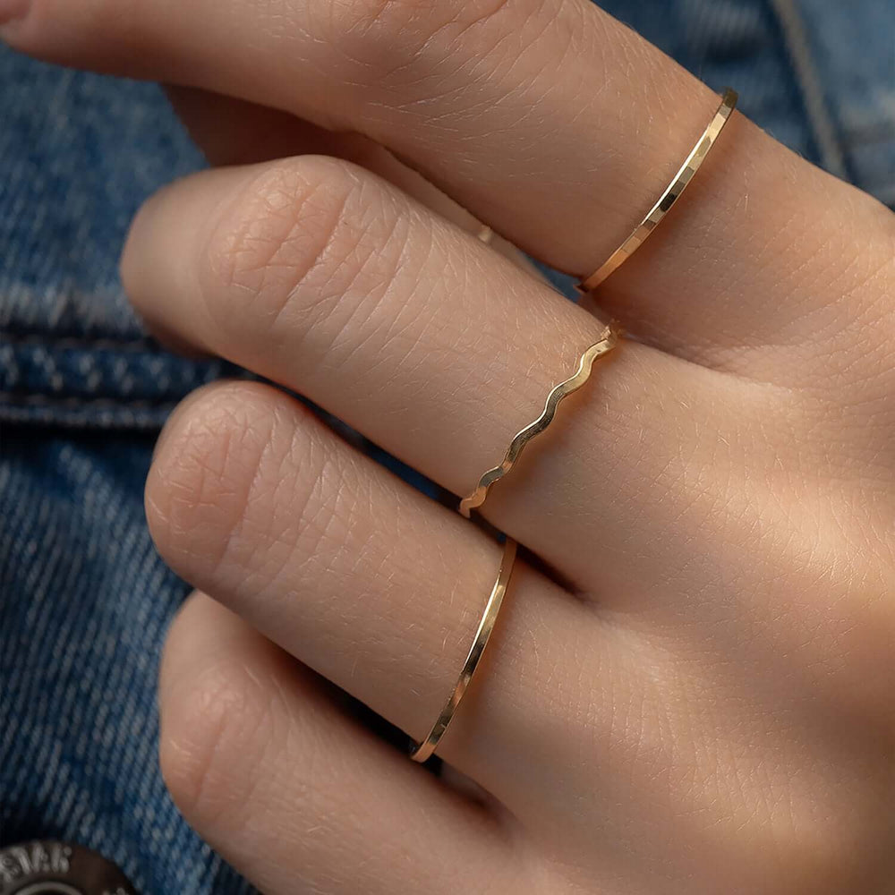 
                      
                        Close-up of a hand wearing two gold rings with a denim background
                      
                    