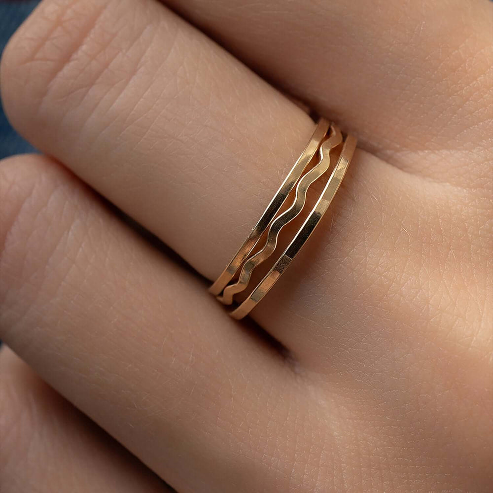 Gold ring with wavy design on a finger