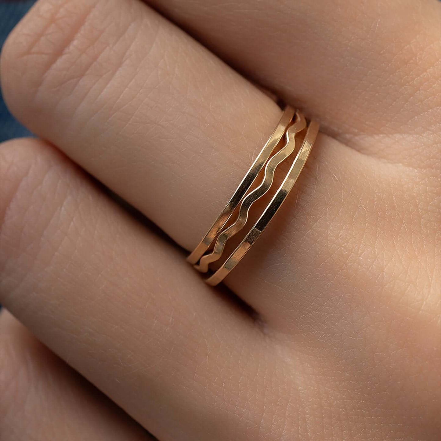 Gold ring with wavy design on a finger