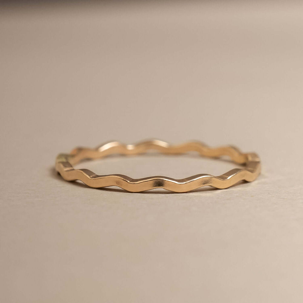 
                      
                        Gold wavy ring on a beige background
                      
                    
