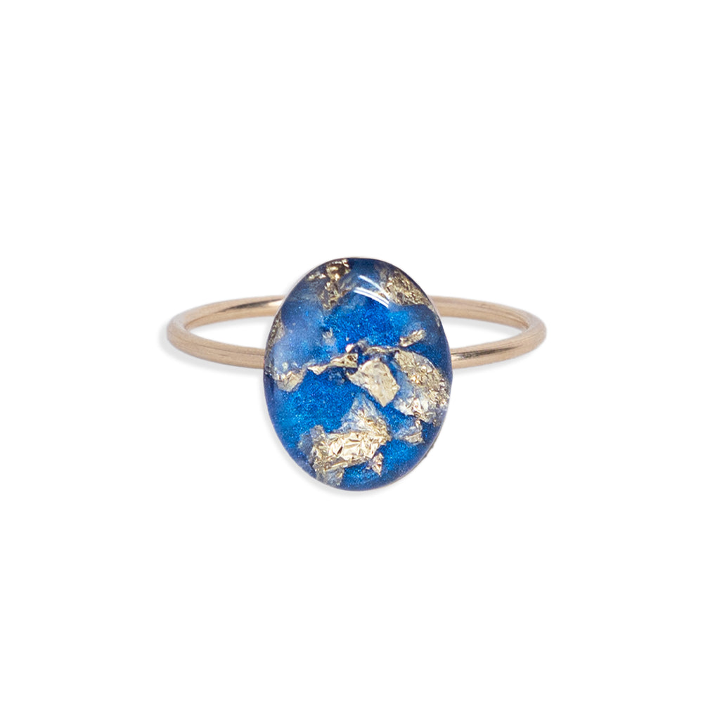 
                  
                    Blue and Gold Oval Ring with gold leaf on a bright blue background sealed in a glass-like resin crystal.
                  
                