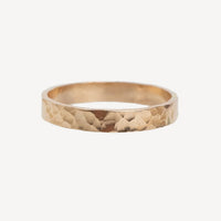Gold ring with a textured surface on a white background