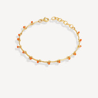 Gold bracelet with small orange beads on a white background