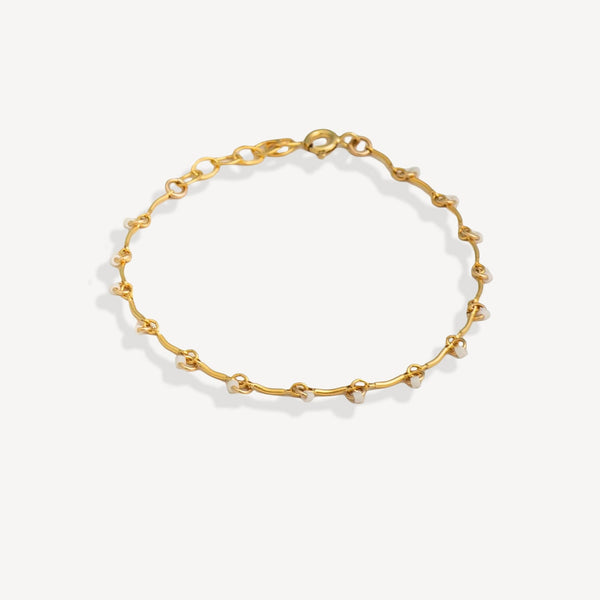 Gold bracelet with small beads on a white background