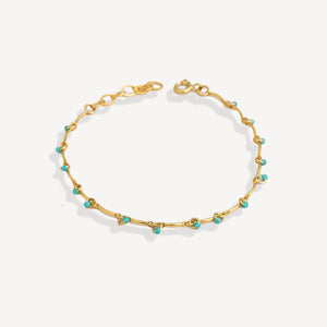 Gold bracelet with turquoise beads on a white background