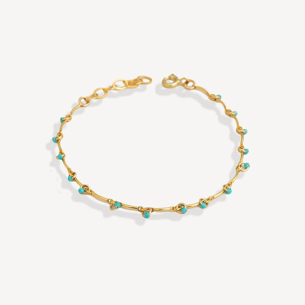 Gold bracelet with turquoise beads on a white background