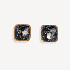 Square-shaped earrings with black and gold design on a white background