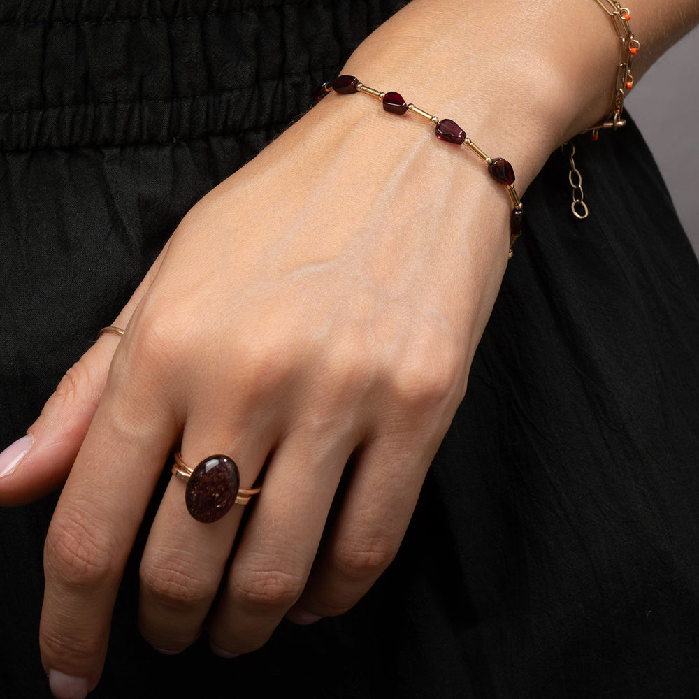 A gold chain necklace featuring faceted dark red Garnet beads, displayed on a clean off-white background.