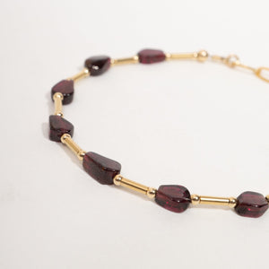 A Garnet beaded chain necklace featuring dark burgundy glass beads and polished gold-toned metal links, displayed on a clean white background.