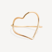 A delicate gold open heart cuff ring with a polished finish, displayed on a clean, light off-white background.