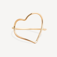 A delicate gold open heart cuff ring with a polished finish, displayed on a clean, light off-white background.