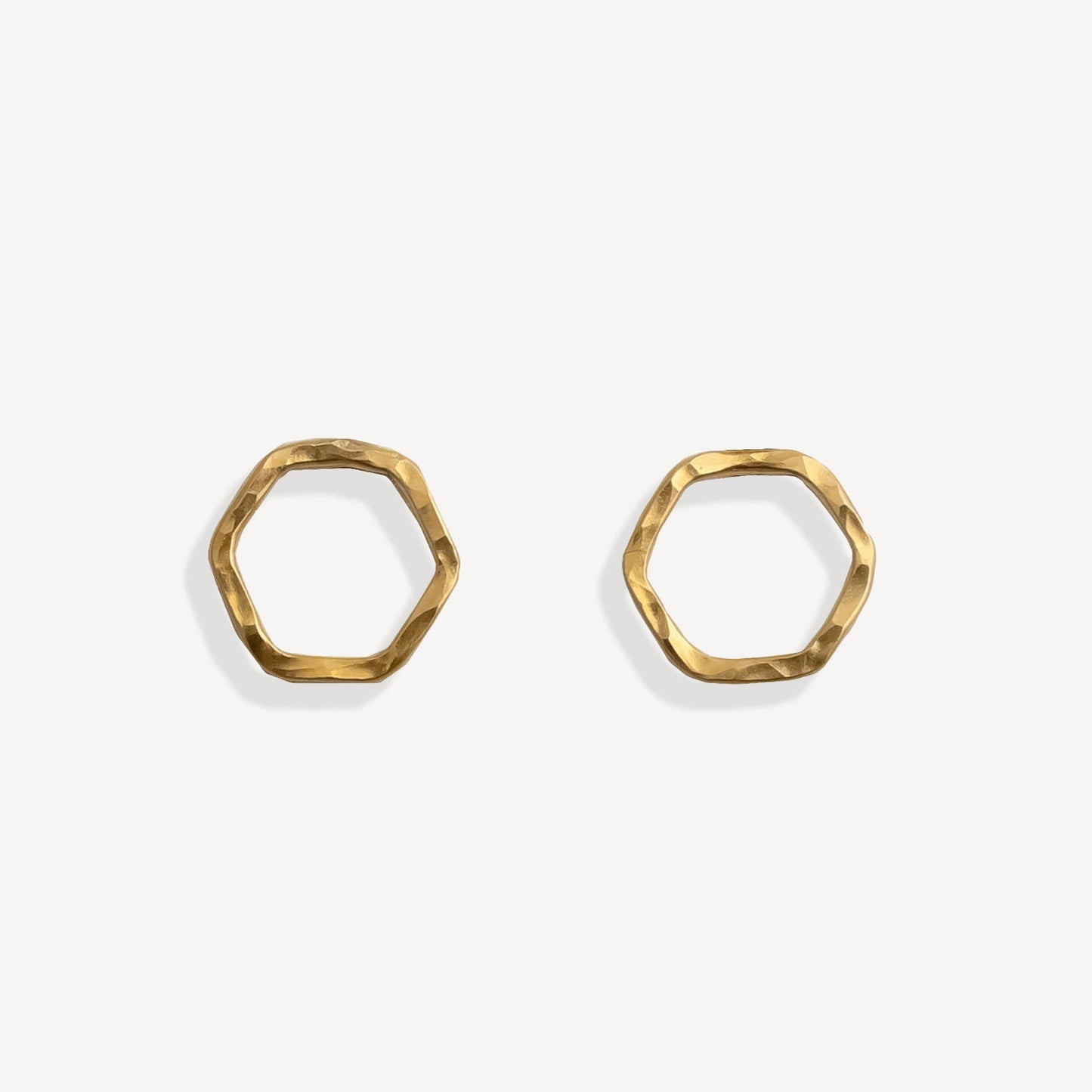 Pair of gold hexagonal earrings on a white background