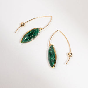 Gold hoop earrings with green gemstones on a white background
