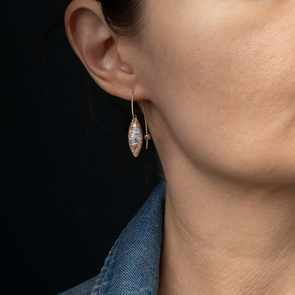 A pair of gold hoop earrings with marquise-shaped black dangles featuring embedded gold leaf, shown against a light gray background.