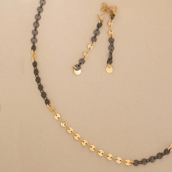 Gold and black chain necklace on a beige background