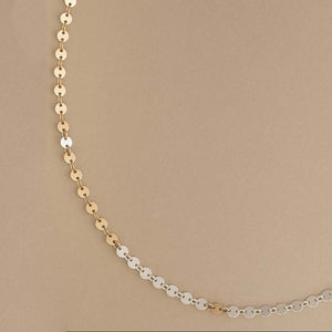 Gold and silver chain necklace on a beige background