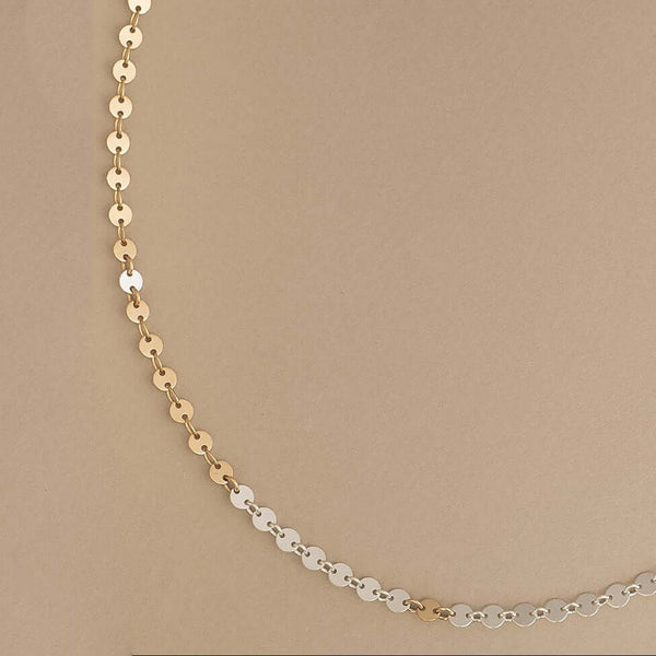 Gold and silver chain necklace on a beige background