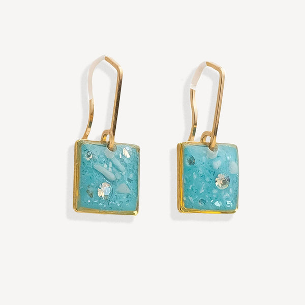 Pair of earrings with turquoise square stones and gold accents on a white background