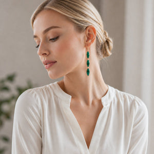 Woman wearing green earrings in a neutral setting