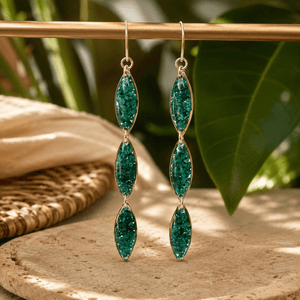 Green gemstone earrings on a wooden surface with a natural background