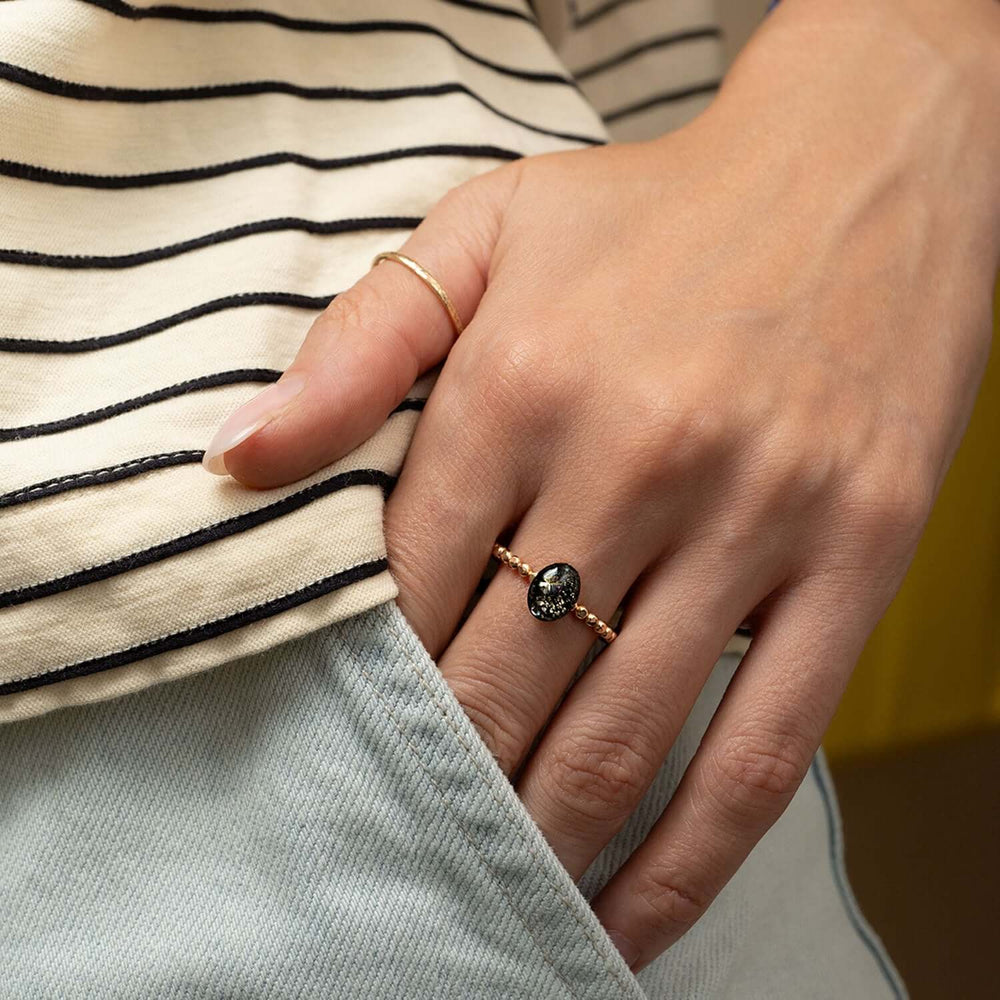 Gold ring with a black gemstone and diamonds on a white background
