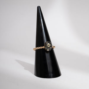 Ring on a black cone-shaped stand against a light gray background