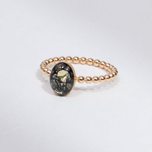 Rose gold ring with a black gemstone on a light gray background