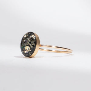 Gold bracelet with a round, dark gemstone on a light gray background