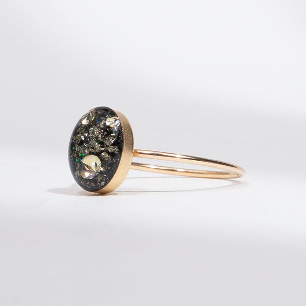 Gold bracelet with a round, dark gemstone on a light gray background