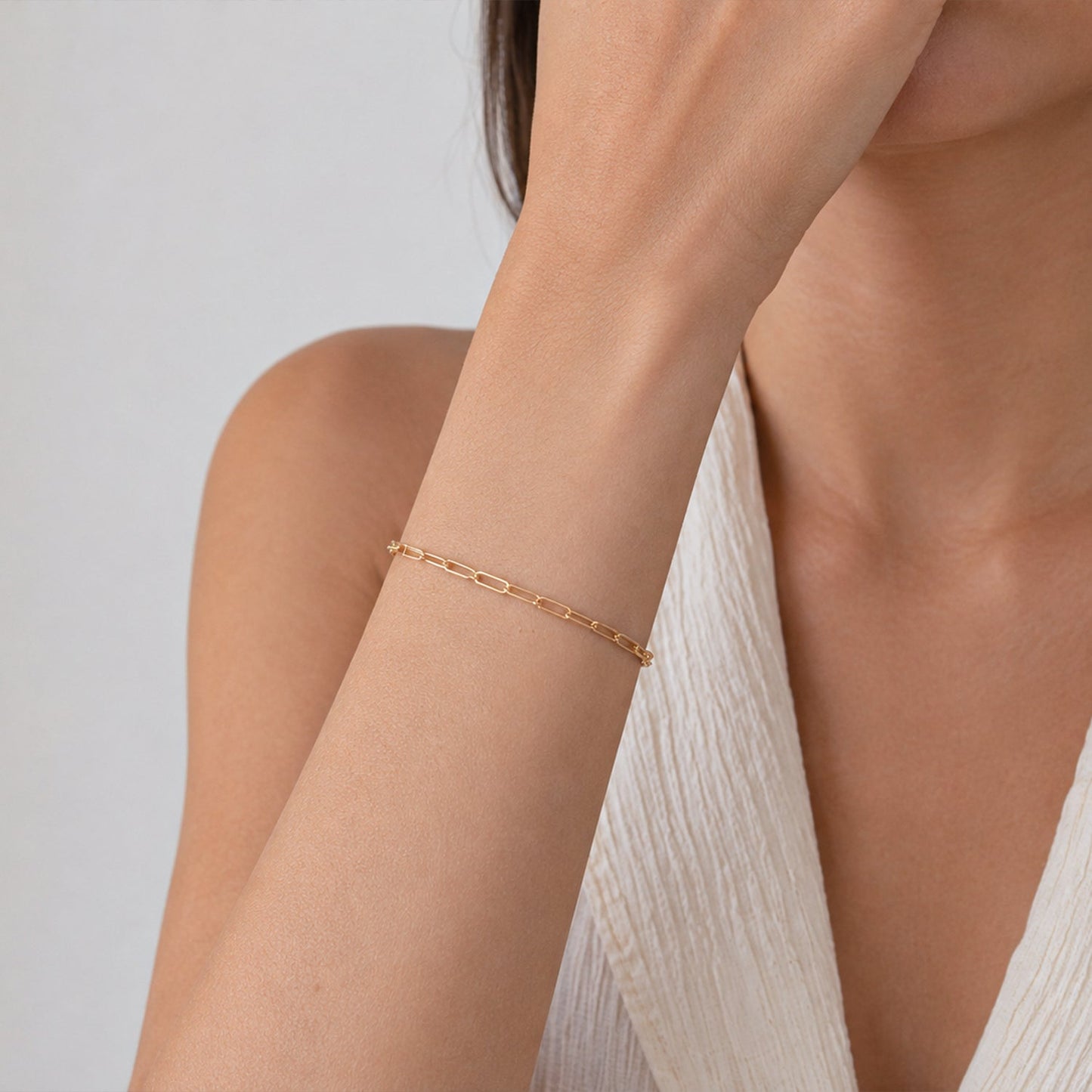 Gold bracelet on a person's wrist against a neutral background