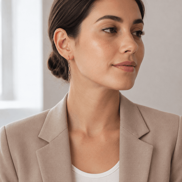 Woman wearing gold earrings with a neutral background