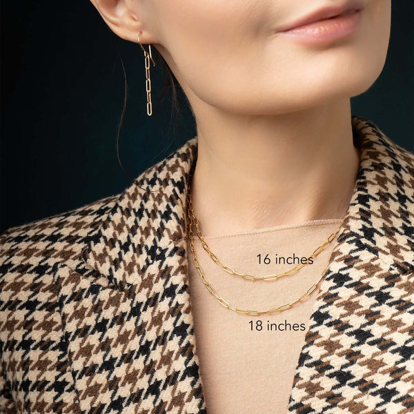 Close-up of a person wearing gold necklaces with measurements labeled, against a dark background.