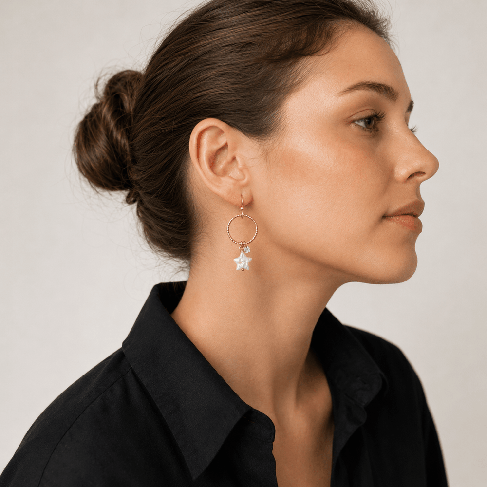 Rose gold hoop earrings with star-shaped charms on a white background
