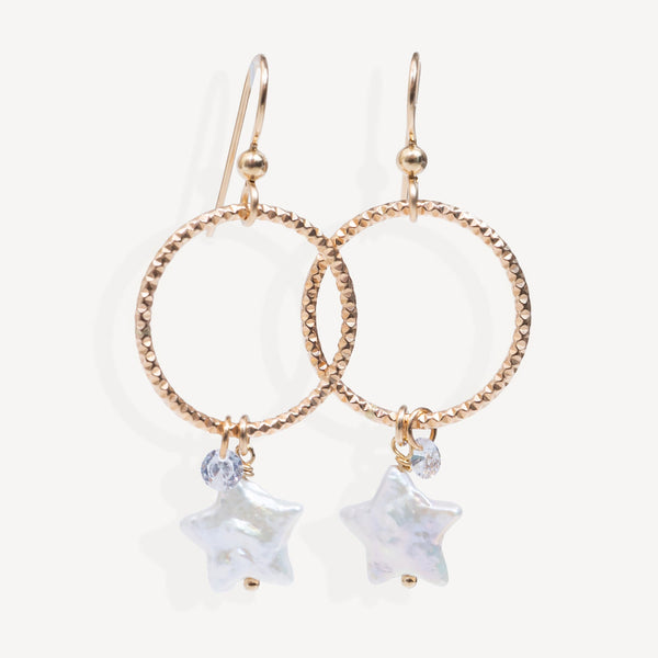Rose gold hoop earrings with star-shaped charms on a white background