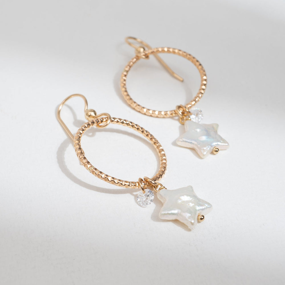 Rose gold hoop earrings with star-shaped charms on a white background