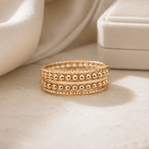Stack of gold rings on a beige fabric background