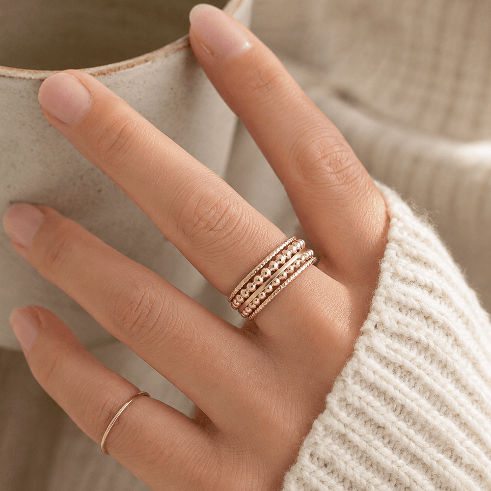 Hand wearing a gold ring with a blurred background