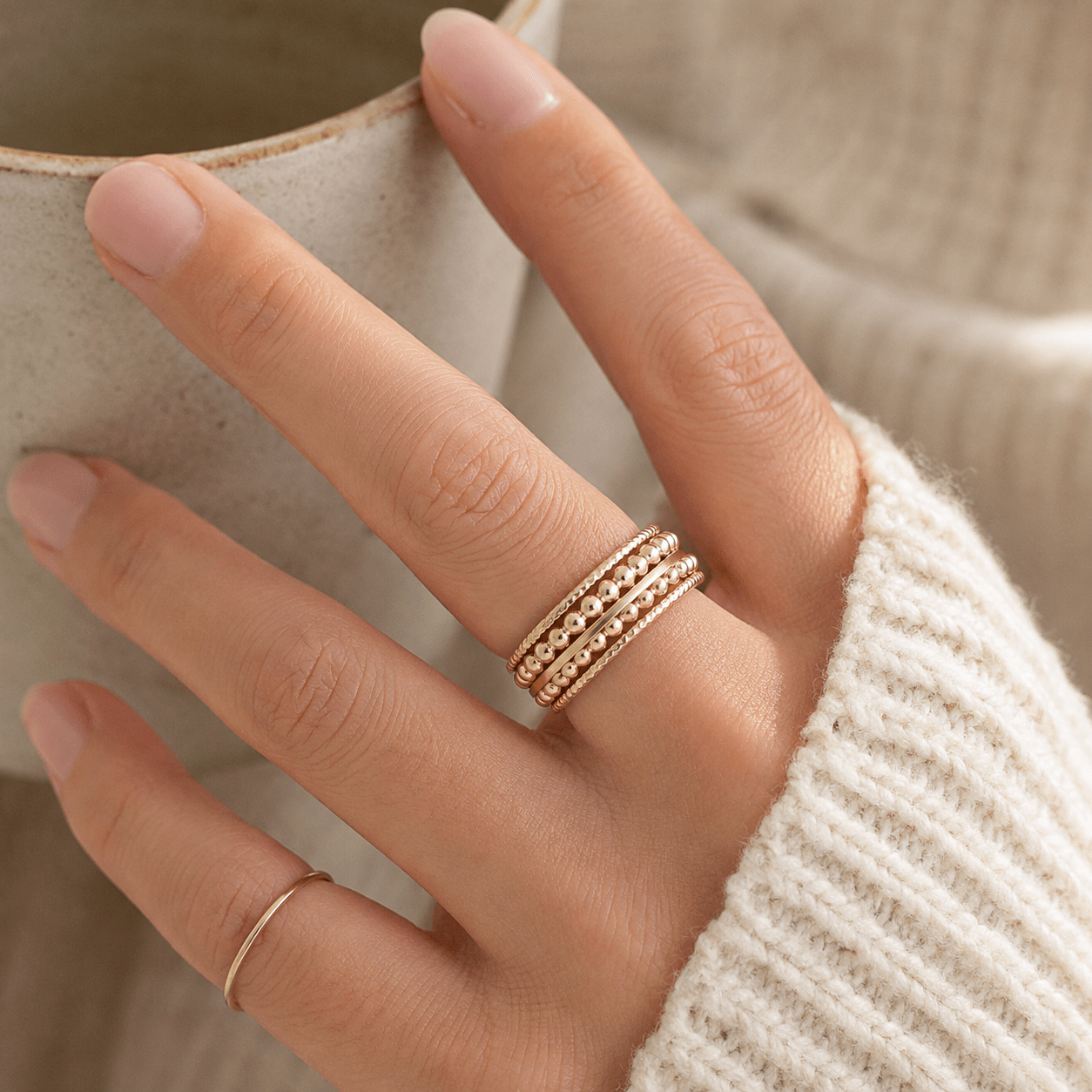 Hand wearing a gold ring with a blurred background