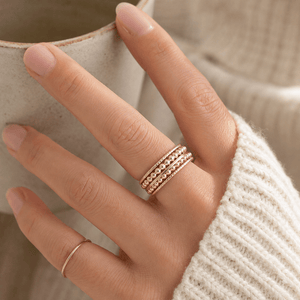 Hand wearing a gold ring with a blurred background