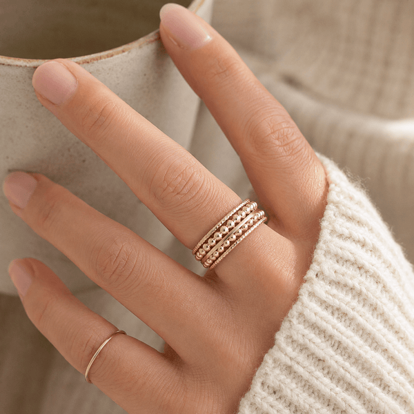 Hand wearing a gold ring with a blurred background